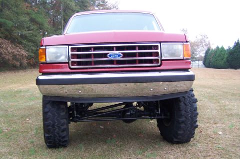 1990 Ford Bronco - Front view of a red 1990 Ford Bronco, modified with large off-road tires.