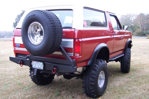 1990 Ford Bronco - Rear view of a red 1990 Ford Bronco showing its spare tire and custom bumper.