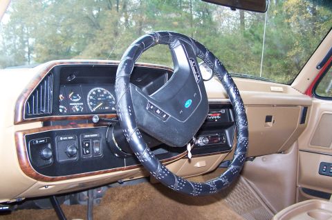 1990 Ford Bronco - The interior of a 1990 Ford Bronco shows tan upholstery and a black steering wheel cover.