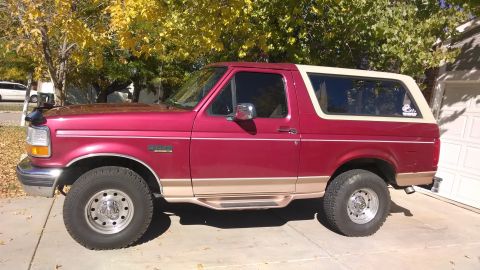 1995 Ford Bronco - maroon full-size Ford Bronco with two-tone trim and a white removable hardtop parked in a residential driveway.