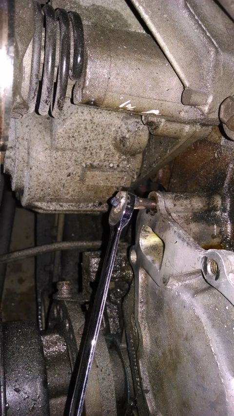 1995 Ford Bronco - Close-up of a wrench working on a mechanical component of an engine.