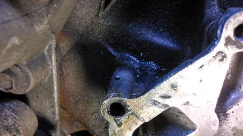 1995 Ford Bronco - Close-up view of an engine block casting, showing metal texture and some oil residue.