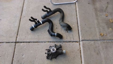 1995 Ford Bronco - Engine water pump and hoses are laid out on a concrete surface.