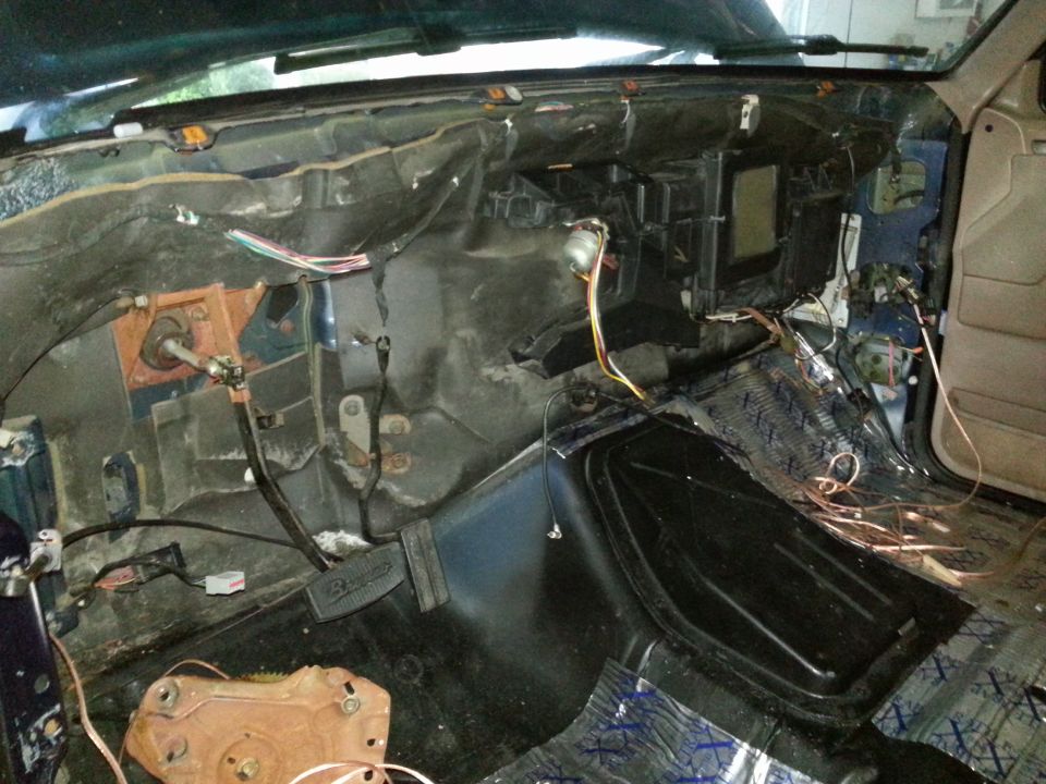Disassembled 1994 Ford Bronco interior showing exposed dashboard, wiring, and sound dampening material on the floor
