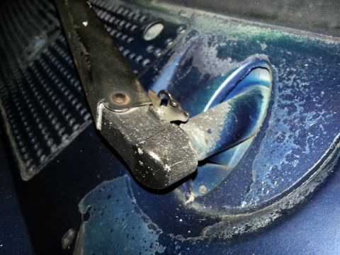 1994 Ford Bronco - Windshield wiper arm base on a blue vehicle, showing wear and paint chipping.