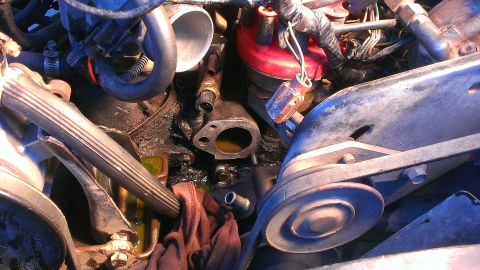 1986 Ford Bronco - Thermostat housing removed from engine bay, revealing coolant and engine components.