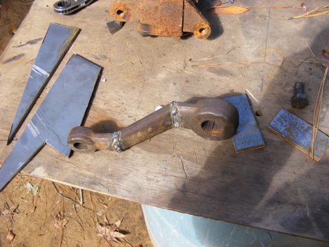 Rusty metal steering arm with splines on a wooden surface.