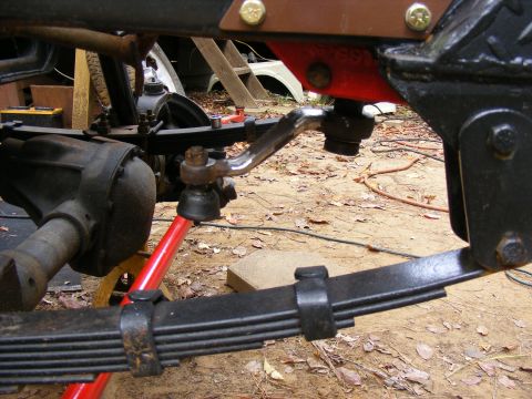 Close-up of vehicle suspension and steering parts: leaf springs, differential, tie rod.