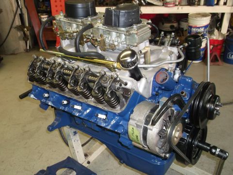 1967 Ford Mustang - A blue V8 engine with dual carburetors and an alternator is shown in a workshop setting.