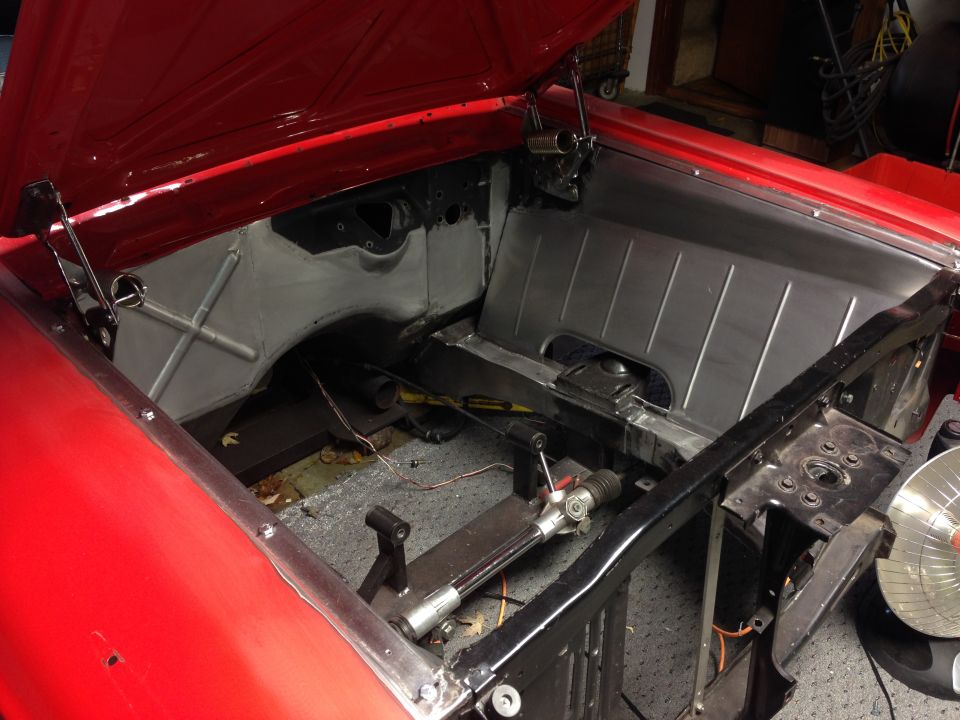 1964 Ford Fairlane engine bay with firewall and inner fenders exposed during restoration.
