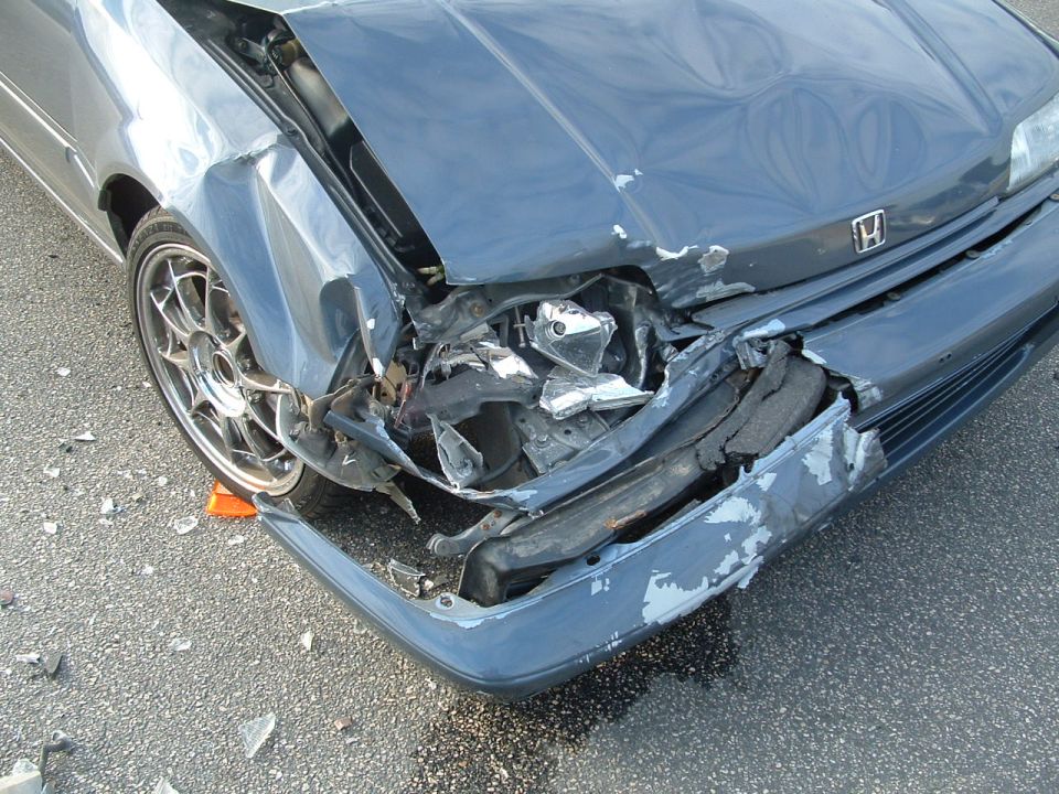 Front collision damage on a blue Honda hatchback with crumpled bumper and fender