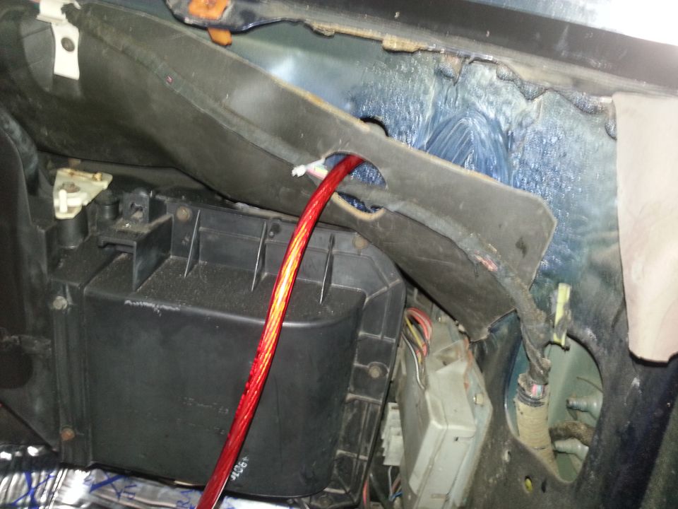 Car interior showing HVAC ducting, wiring, and a red cable running through a hole