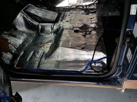 1994 Ford Bronco - The interior floor of a vehicle is covered in sound deadening material, with various wires running across it.