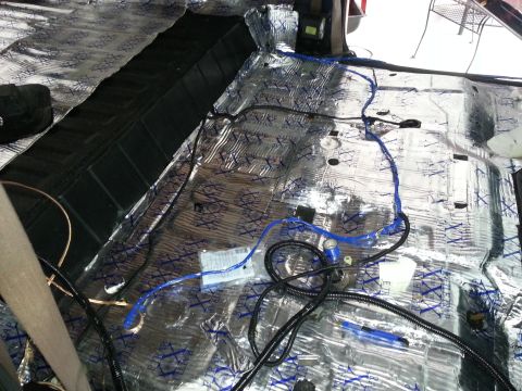 1994 Ford Bronco - Photograph of a vehicle floor pan covered with foil sound-deadening mat and wiring harness, not a technical document.