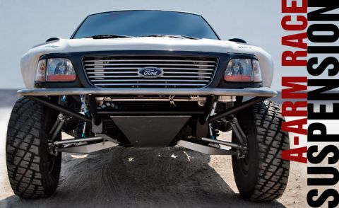 1988 Ford Bronco - Front view of a modified Ford truck with a large A-arm race suspension and aggressive off-road tires. The vehicle has a white body with a b…