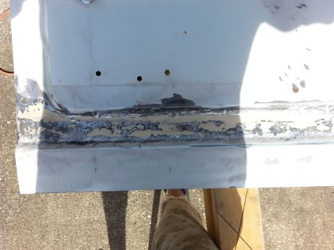 1992 Ford Bronco - Close-up of a vehicle body panel undergoing rust repair, revealing damaged metal and primer.