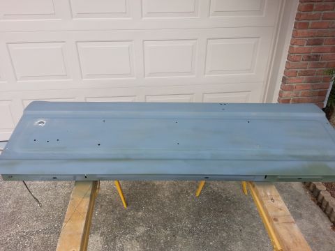 1992 Ford Bronco - A vehicle tailgate, prepped for repair, rests on sawhorses before a garage door.