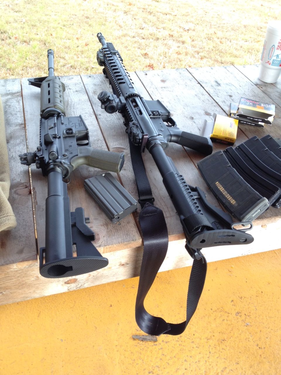 Two black rifles with loaded magazines on a wooden table