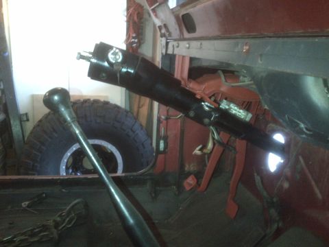 1985 Jeep CJ7 - Interior view of a vehicle's steering column and gear shift lever, with a tire visible in the background.