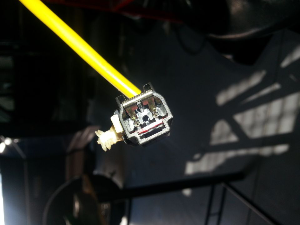 Electrical connector with a yellow wire attached, showing metal contacts inside a black housing