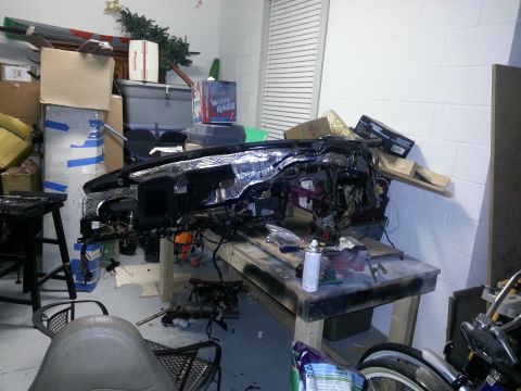 1994 Ford Bronco - A disassembled vehicle dashboard is shown with its internal components exposed, resting on a workbench.