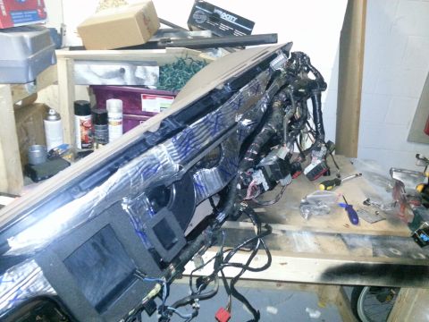 1994 Ford Bronco - The dashboard is disassembled, revealing extensive wiring and sound dampening material, suggesting a repair or modification process.