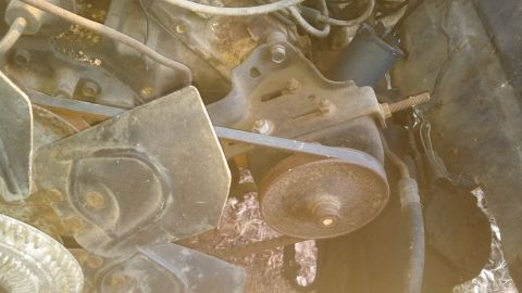 1979 Ford Bronco - The engine compartment shows a worn belt and pulley system, with visible rust on metal components.