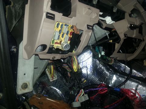 1994 Ford Bronco - Photograph of a vehicle fuse panel and wiring harness behind the dash during a sound-deadening install, not a chart document.