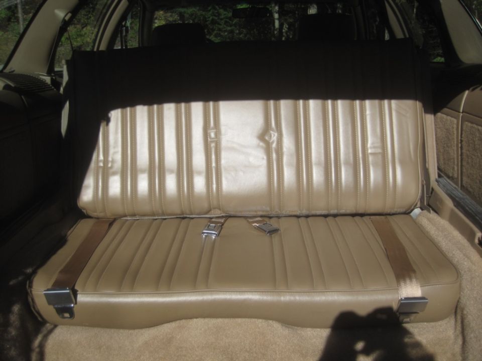 Tan vinyl rear bench seat and seat backs in a vehicle.