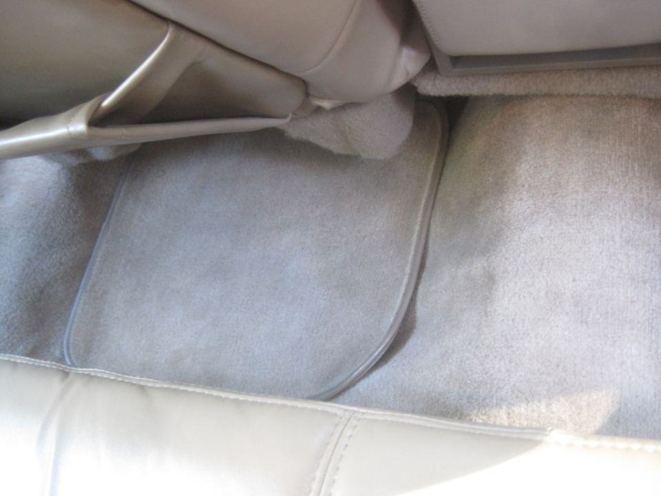 Interior of a car showing beige carpet and floor mat.