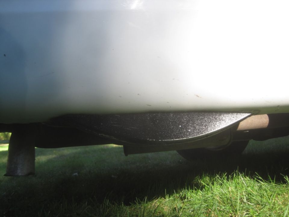 Underside of a white vehicle showing black undercoating and exhaust pipe.
