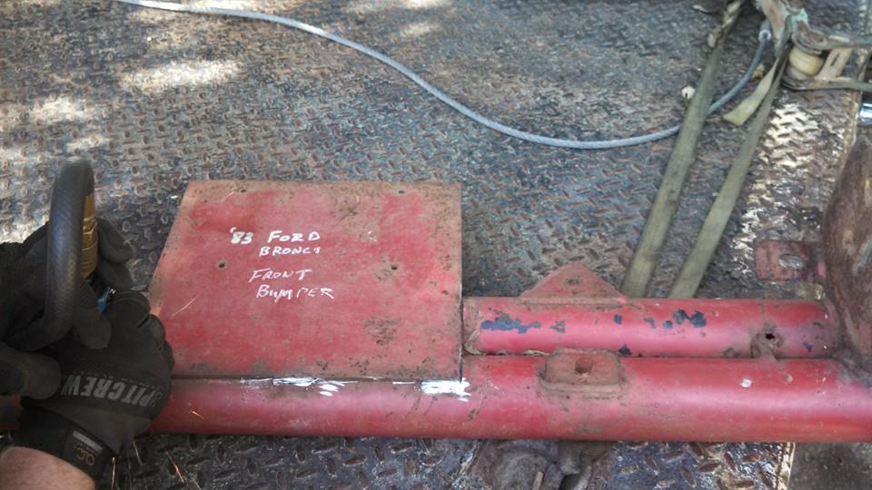 Close-up of a red '83 Ford Bronco front bumper with handwritten text.