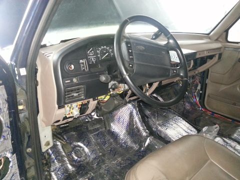 1994 Ford Bronco - Photograph of a truck cab dash and steering wheel over foil sound-deadening, not a technical document.