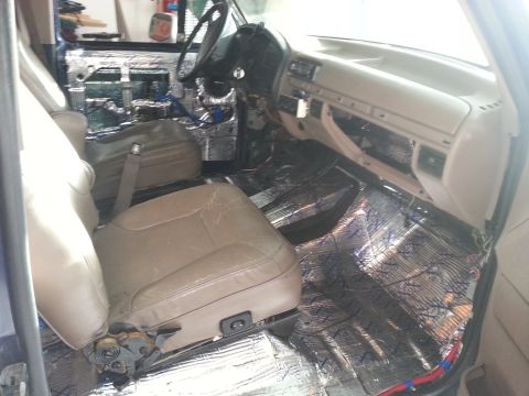 1994 Ford Bronco - Photograph of a truck cab interior with seats, dash, and foil sound-deadening, not a technical document.