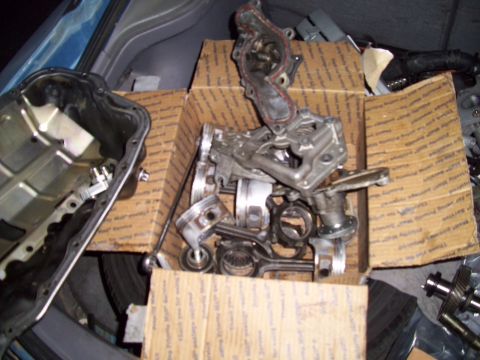 1995 Ford Probe - A collection of engine parts, including pistons, crankshafts, and an oil pan, are arranged in cardboard boxes inside what appears to be the…