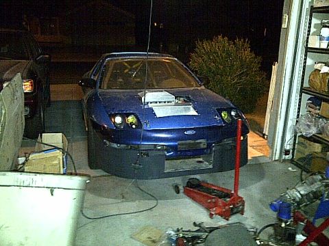 1995 Ford Probe - A blue Ford Probe is parked in a garage with its hood open, revealing an intercooler. A red floor jack is positioned under the front of the…