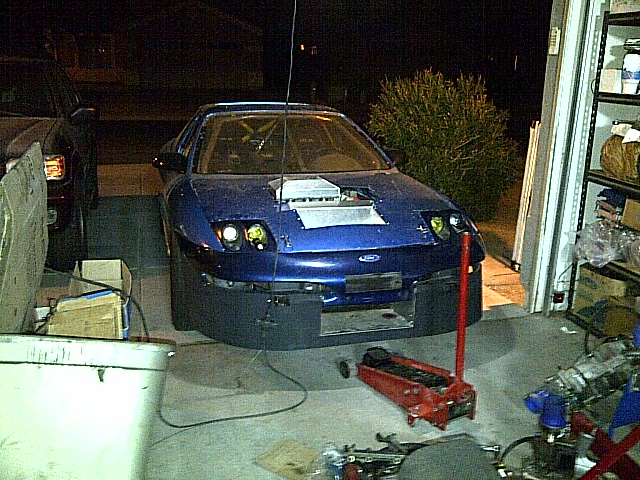 Blue Ford Probe with intercooler visible, in a garage with a floor jack and parts.