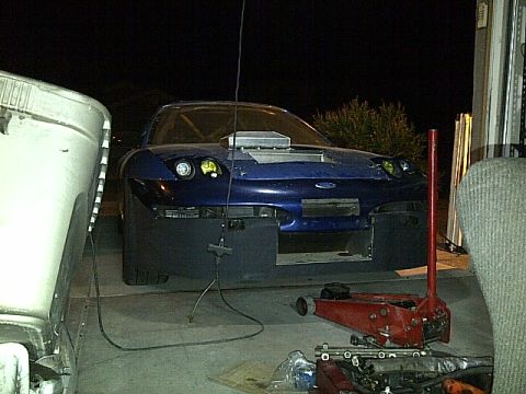 1995 Ford Probe - A dark blue modified sports car is parked in a garage at night. The car has a large hood scoop and appears to be undergoing some form of mo…