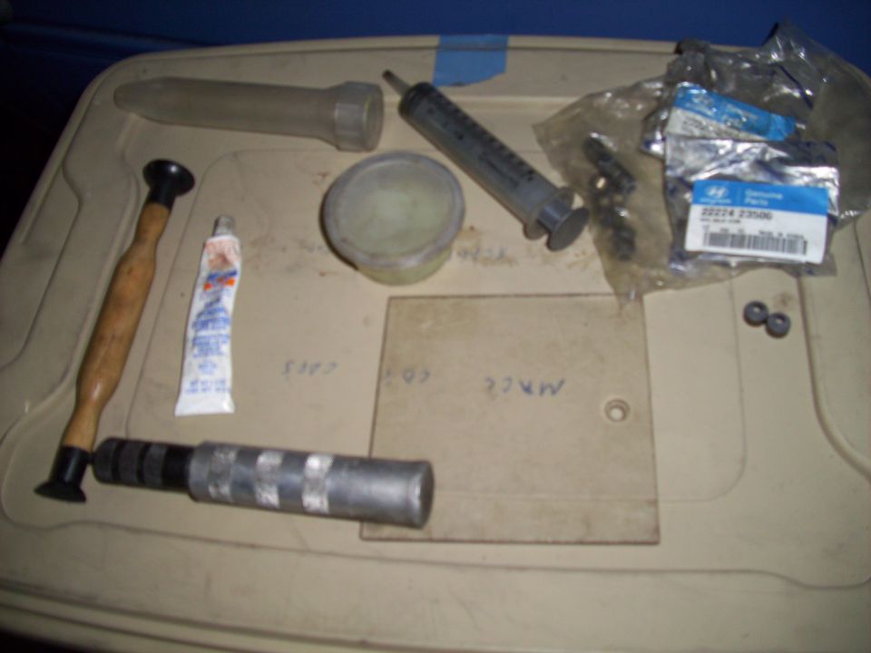 Tools and car parts on a beige surface.