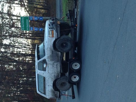 1994 Ford Bronco - A white 1994 Ford Bronco is seen loaded onto a trailer on a roadside.