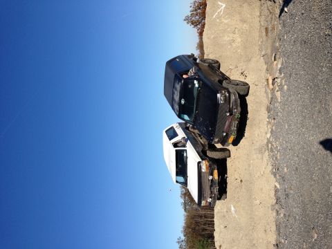 1995 Ford Bronco - Two SUVs are stuck on a steep dirt embankment under a clear blue sky.