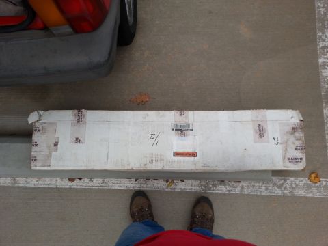 1965 Ford Mustang - A long, white cardboard box with "MAGNUM" tape is laid on the ground next to a portion of a vehicle's rear bumper and taillight. The box ap…