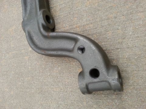 1965 Ford Mustang - A gray metal automotive part, possibly a suspension component, is shown on a concrete surface. The part has several holes and a curved shap…