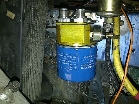 1995 Ford Probe - A close-up view shows a blue oil filter with Hyundai and Kia Motors branding, mounted to a yellow adapter with silver fittings. The filter…