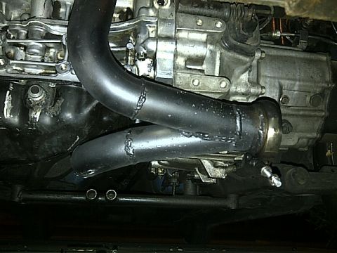 1995 Ford Probe - A close-up view of the exhaust manifold and part of the transmission of a vehicle. The exhaust pipes are black and appear to be custom-weld…