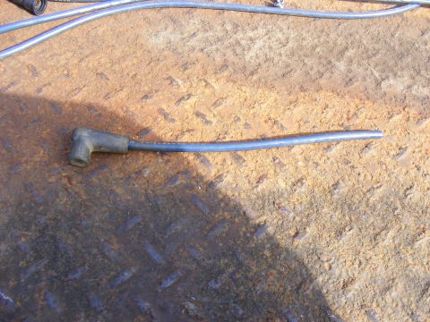 Blue spark plug wire with black boot on rusty metal surface