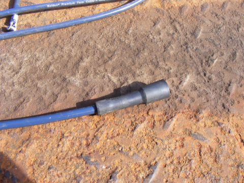 Blue spark plug wire with black boot on rusty surface