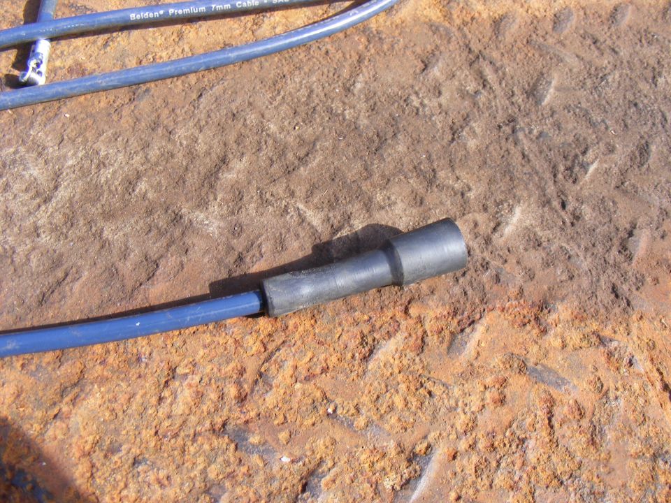 Blue spark plug wire with black boot on rusty surface