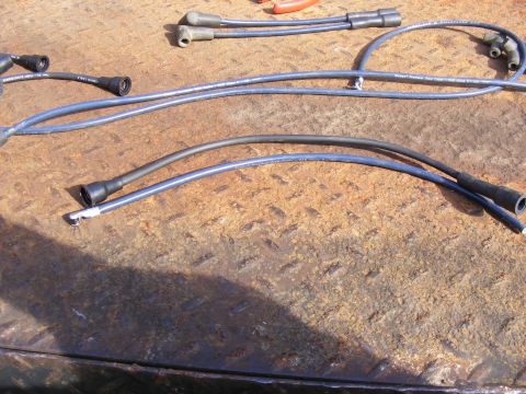 Blue and black spark plug wires on a rusty metal surface