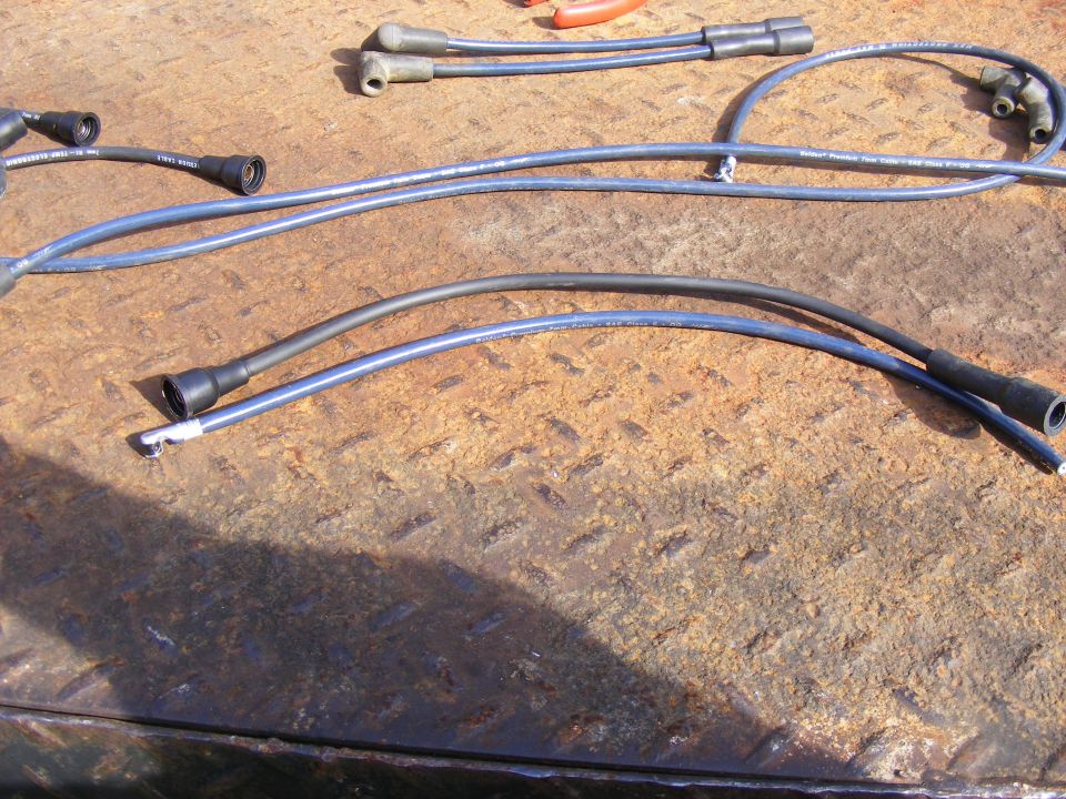 Blue and black spark plug wires on a rusty metal surface